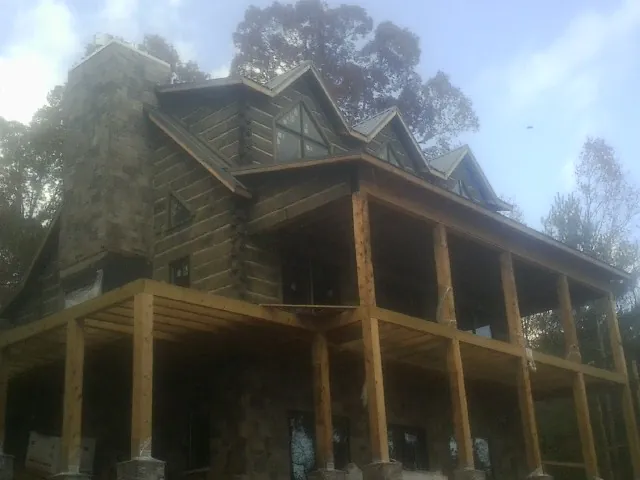 Stone chimney and dormers on a large log home with a timber porch in Verona