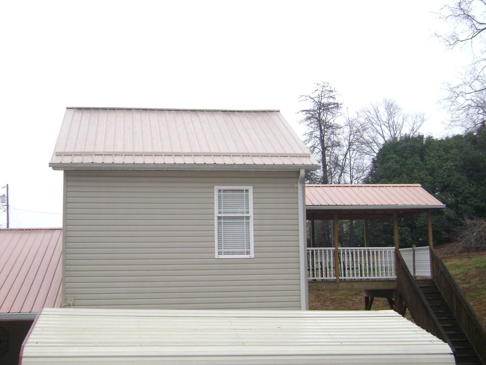 Tan metal roofs on a two story addition and attached porch, from a Roof Replacement job in Verona